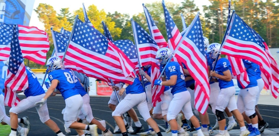 Football Players Carrying American Flag